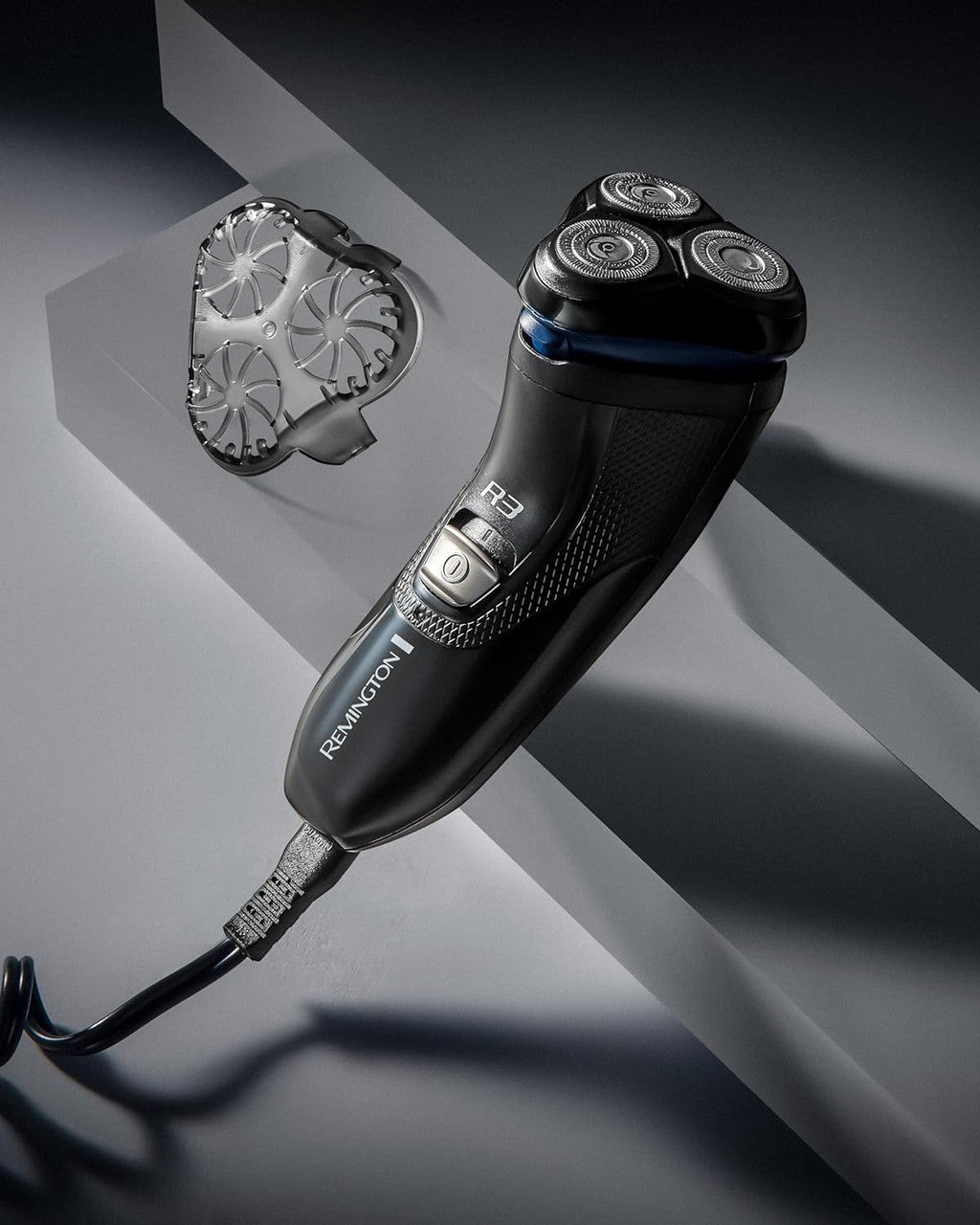 Black electric shaver on a gray surface with a brand logo visible