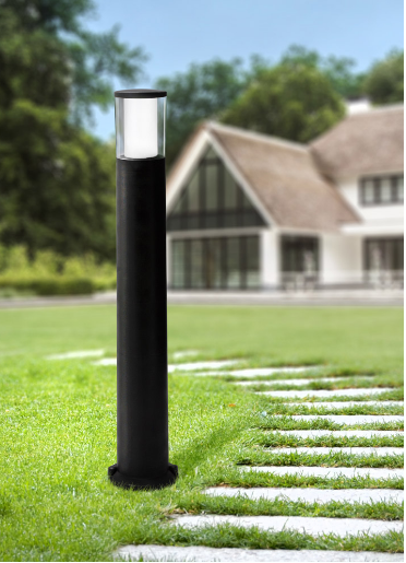 Black garden lamp post on grass with a house in the background