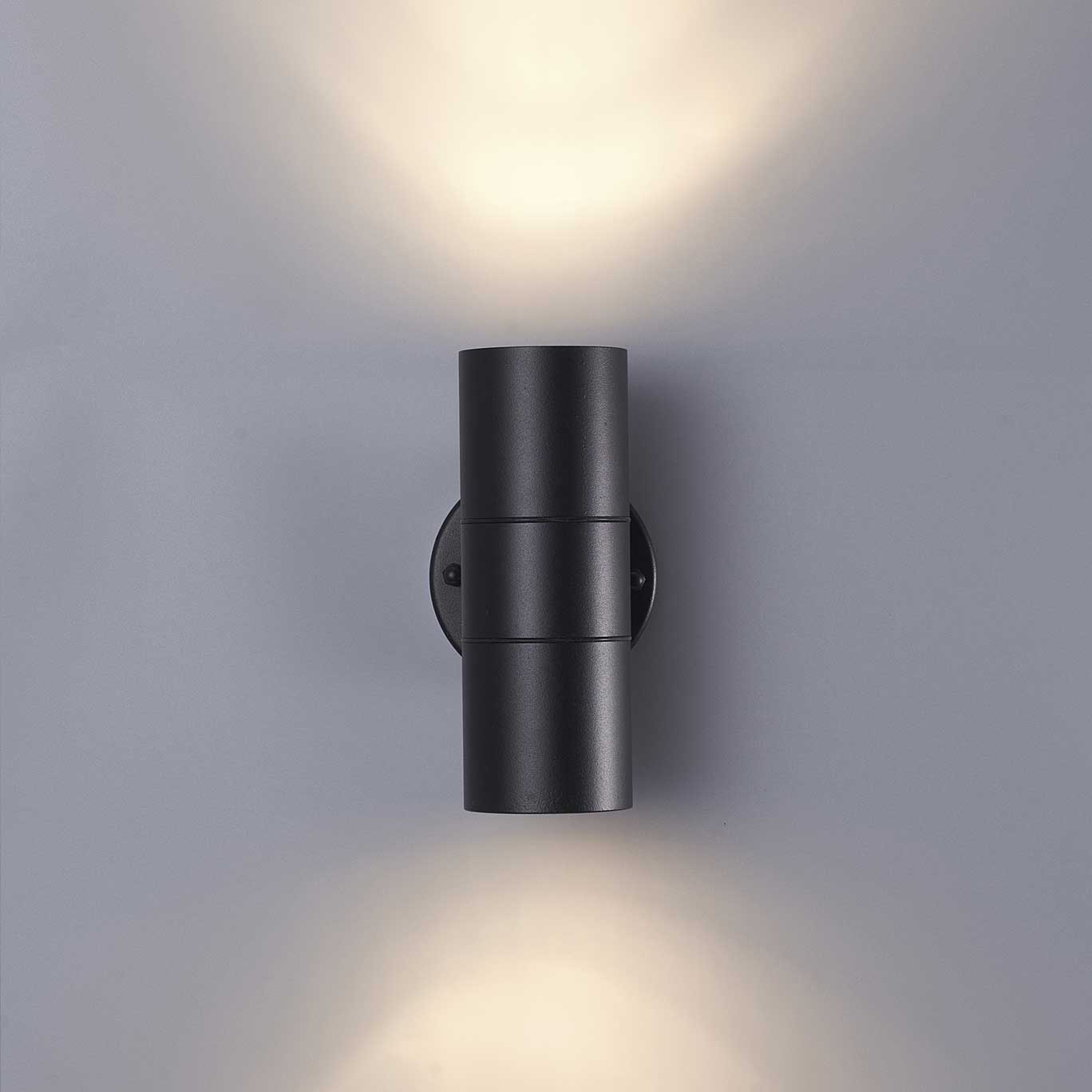 Black wall-mounted outdoor light fixture on a gray wall