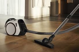 Vacuum cleaner on a wooden floor with a bright room in the background