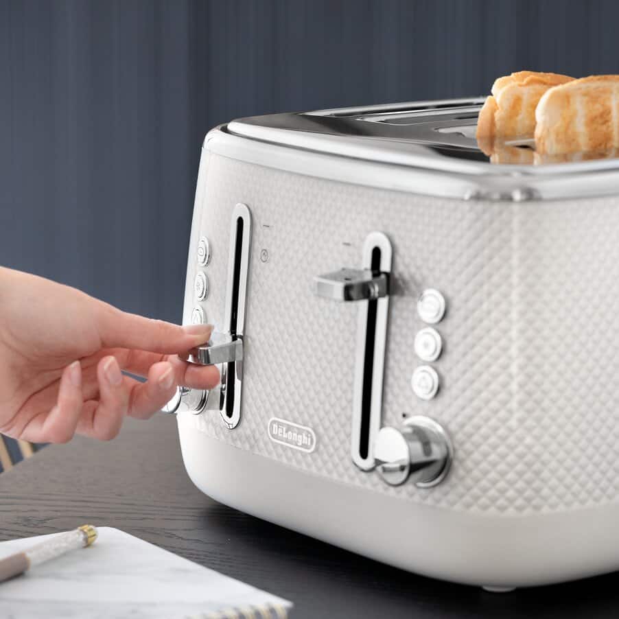 White toaster with a hand inserting a slice of bread