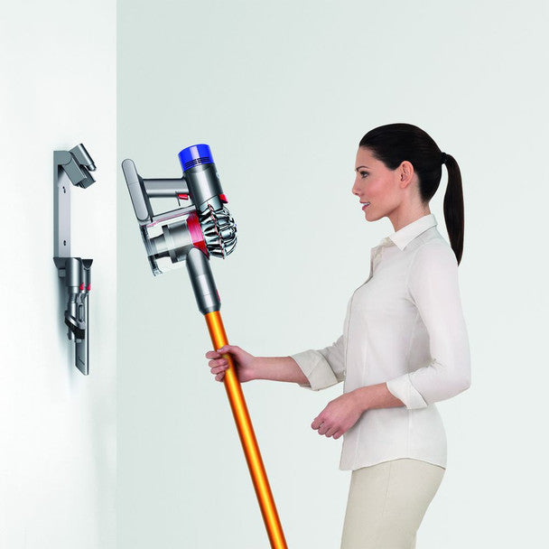 Woman holding a Dyson vacuum cleaner against a white background